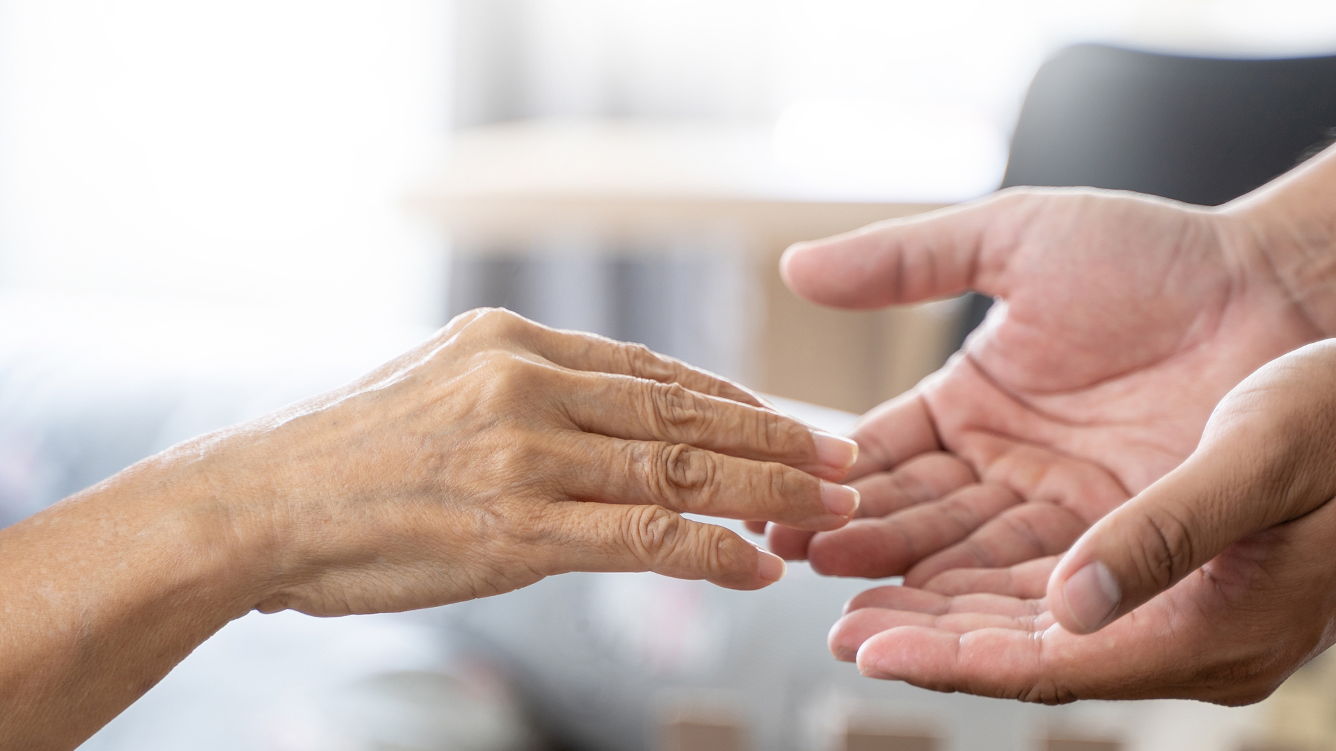 高齢女性の手に両手を差し出す風景